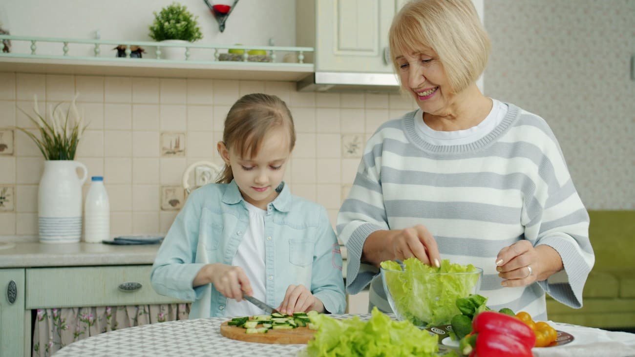 A grandmother and granddaughter preparing a meal together in their kitchen
